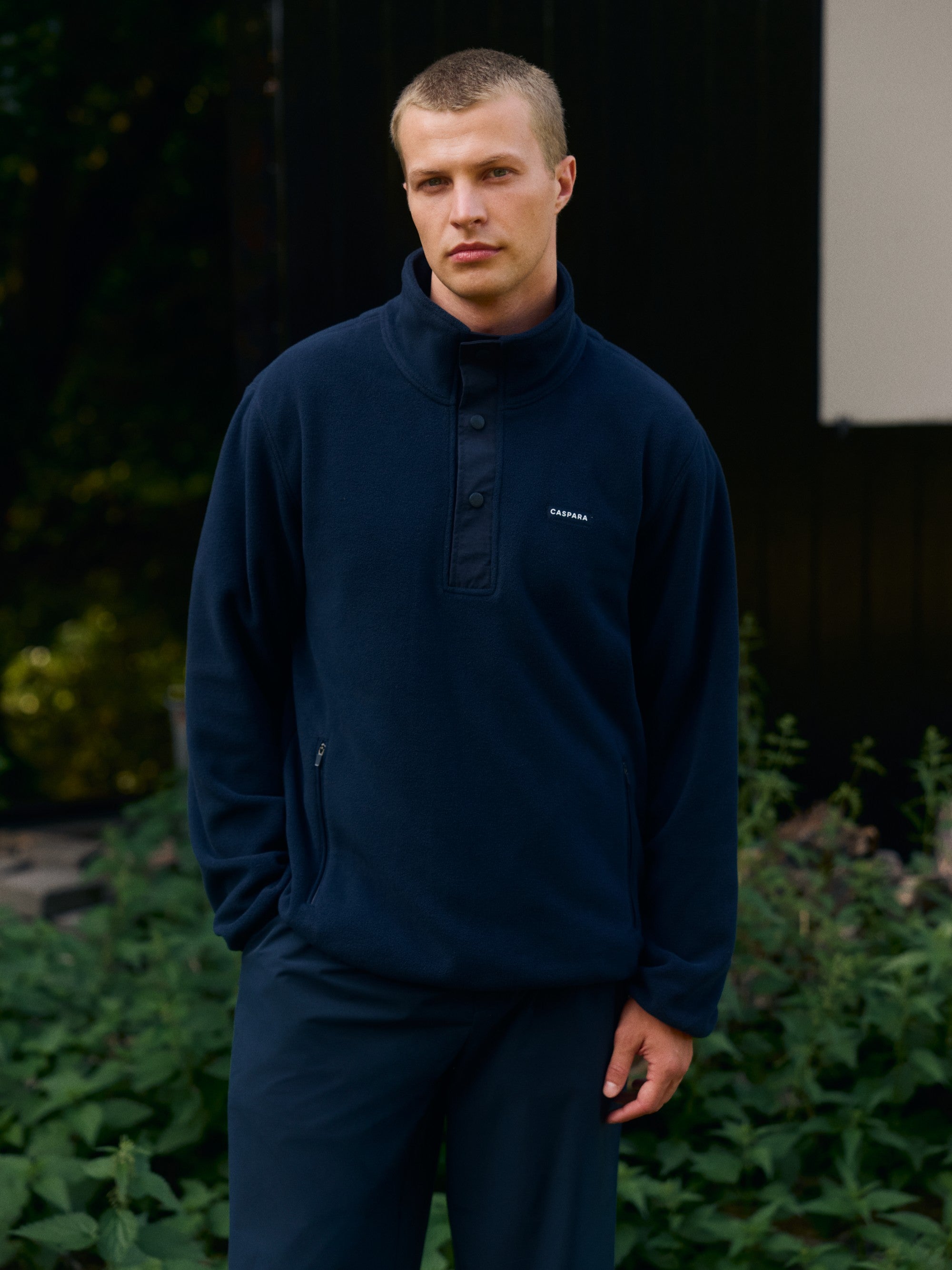 Man wearing a navy CASPARA polar fleece half-snap pullover outdoors.